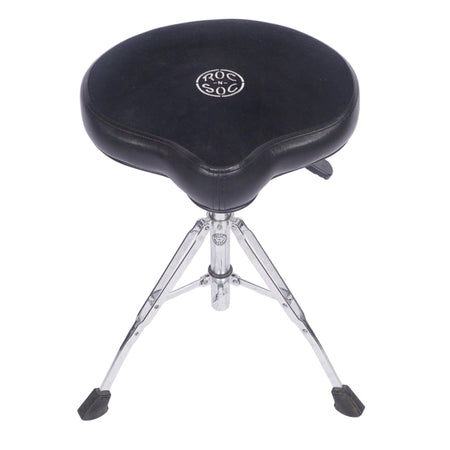 A black drum throne seat with a silver metal tripod base, featuring a circular silver logo on the center of the cushion, photographed against a white studio background.